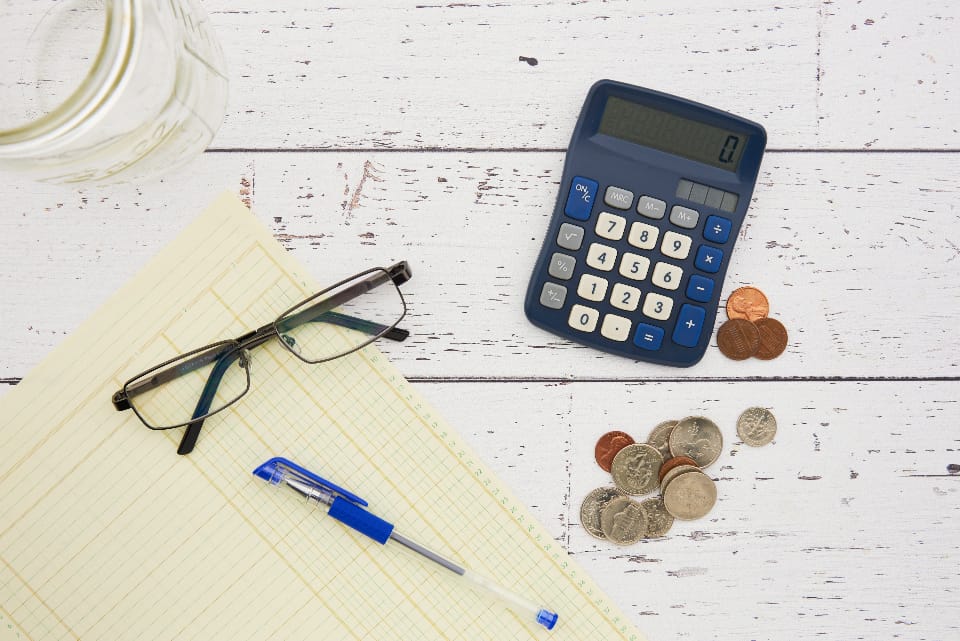 a calculator, notebook, and coins laid out on a desk representing the process of budgeting for SEO in Switzerland