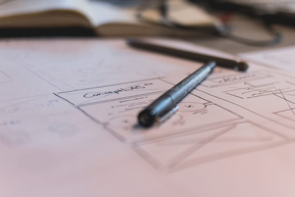 a hand-drawn website wireframe sketch with a pen resting on it, representing the structural planning stage of SEO-friendly web design