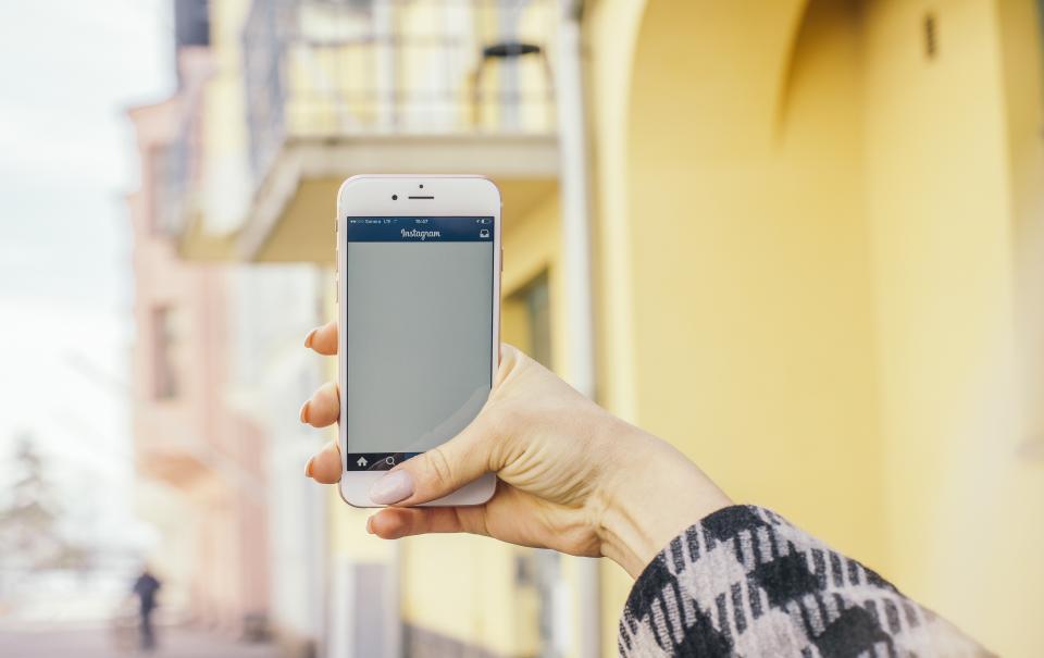 a hand holding a smartphone open to Instagram, representing social media platforms that indirectly influence SEO